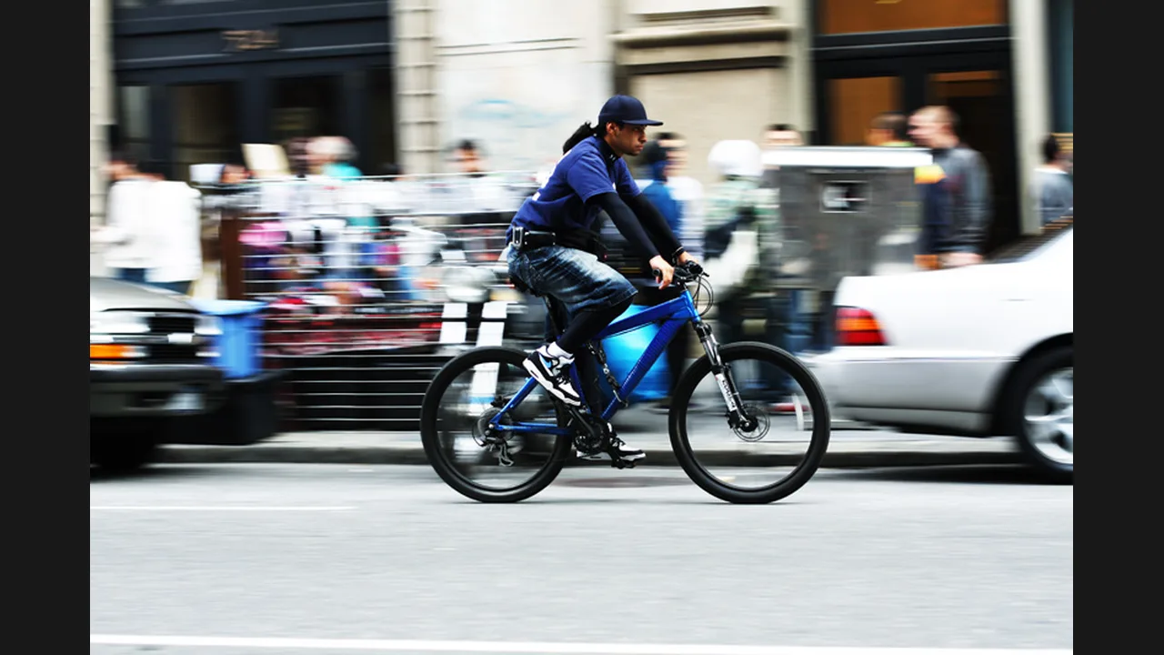 A cyclist riding a blue bicycle through a busy city street