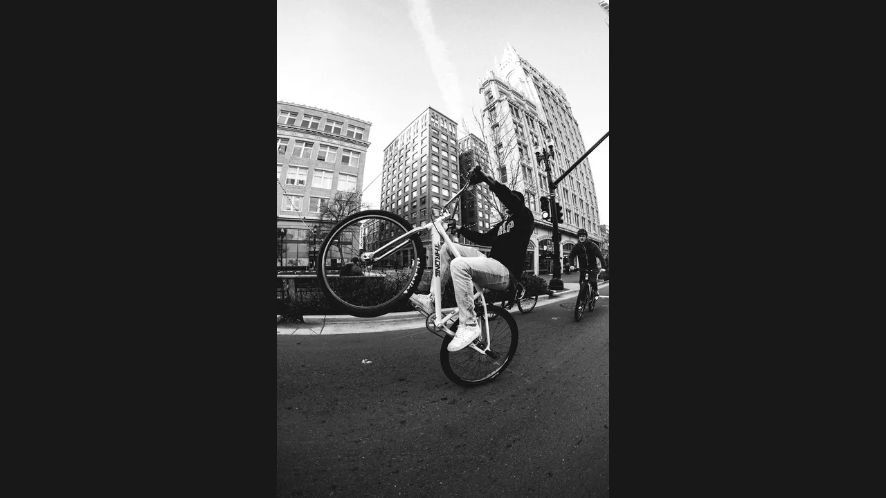 A cyclist doing a wheelie with the front wheel lifted high on a city street