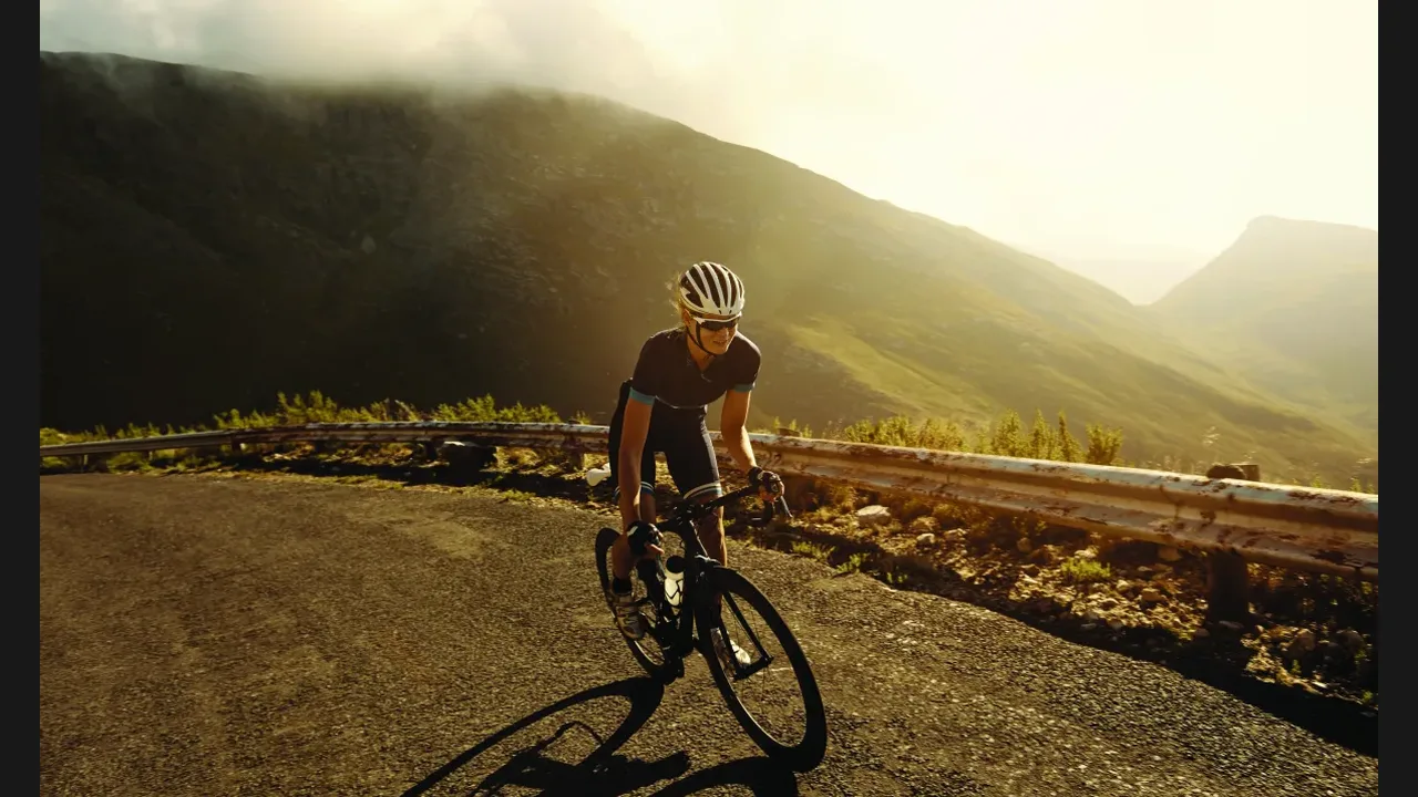 A cyclist climbing a mountain road at sunrise