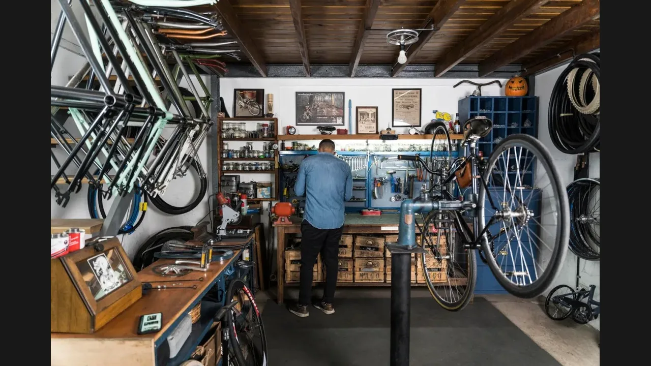 A bicycle mechanic working in a workshop full of frames, wheels and tools